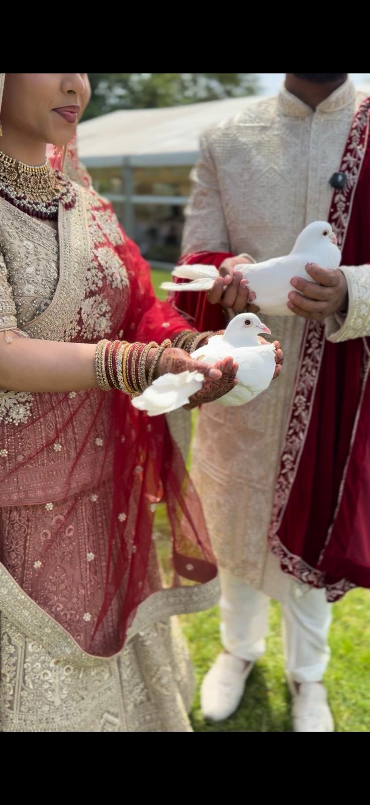 Close view of a bride and groom holding white doves at an outdoor ceremony